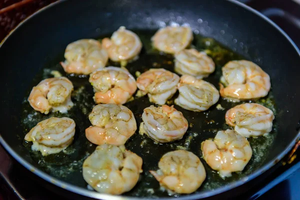 frying shrimps with oil on a pan. seafood prowns cooking