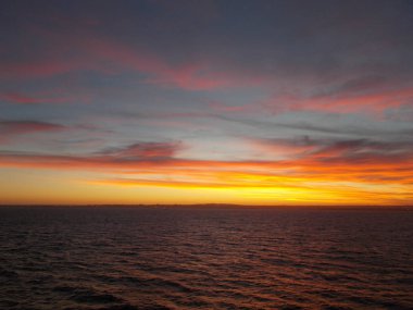 altın renkli buna karşı günbatımı kırmızı mavi bulutlar deniz pürüzsüz bir yüzey üzerinde güneşin son demeti olduğunu.