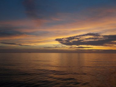 sessiz sessiz akşam su Okyanusun yüzeyine üzerinde altın bulutlar
