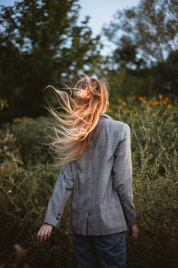 arkadan görünümü gri ceket çayır üzerinde yürümek güneşli gün içinde kadın 