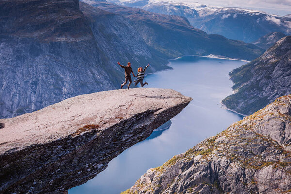 breathtaking view of couple in love enjoying on rock formation of mountain Skjeggedal over  lake Ringedalsvatnet in Trolltunga, Norway