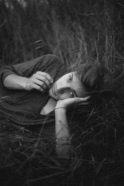 草原の緑の草の上に横たわっている間カメラ目線デニム シャツの男 — ストック写真