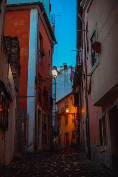 view of narrow street among houses in old quarter at night, Lisbon, Portugal