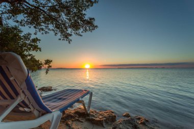 Sunset in Key Largo with chair. Exposure done in theis beautiful island of the Keys, USA.Shot with Canon 5D Mark III, and low ISO, lightly processing for taking advantage of the lovely view and light. clipart