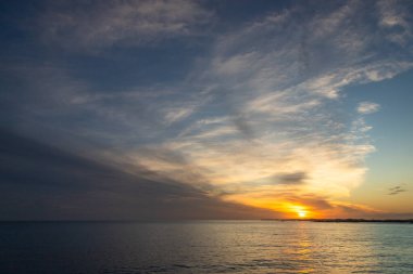 Canlı bulutlar ve sakin sularla altın Atlantik Okyanusu 'nda gün batımı. Seyahat reklamları, refah markalaşması, gevşeme kavramları veya doğa ve özgürlük temalı pazarlama görselleri için ideal.