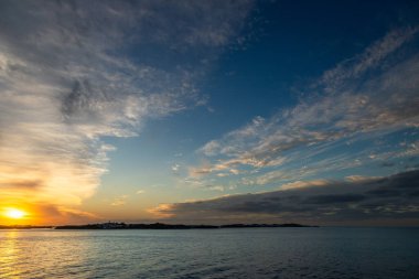 Canlı bulutlar ve sakin sularla altın Atlantik Okyanusu 'nda gün batımı. Seyahat reklamları, refah markalaşması, gevşeme kavramları veya doğa ve özgürlük temalı pazarlama görselleri için ideal.