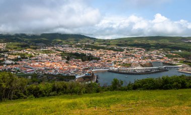 Angra do Heroismo 'nun panoramik görüntüsü Terceira Adası, Azores, Portekiz. Kırmızı çatılar, marina ve yeşil tepeler Monte Brasil 'den Atlantik Okyanusu manzaralı..