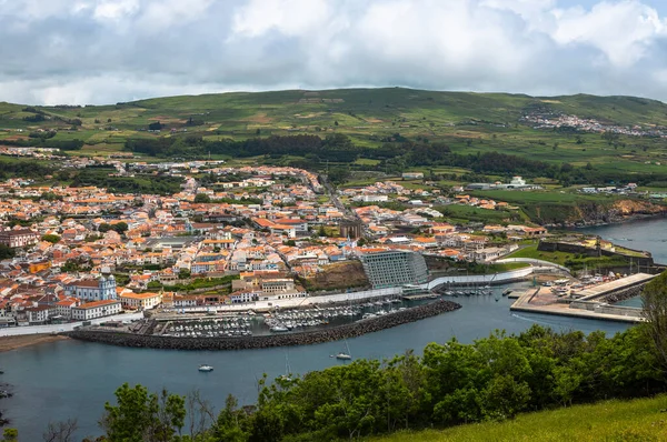 Angra do Heroismo 'nun panoramik görüntüsü Terceira Adası, Azores, Portekiz. Kırmızı çatılar, marina ve yeşil tepeler Monte Brasil 'den Atlantik Okyanusu manzaralı..