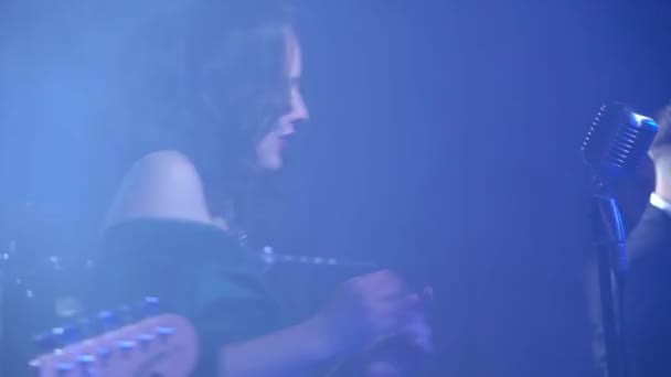 ステージ歌うマイクとジャズバンドの背景に青い Ligts のダンスに美しい少女が立っています — ストック動画