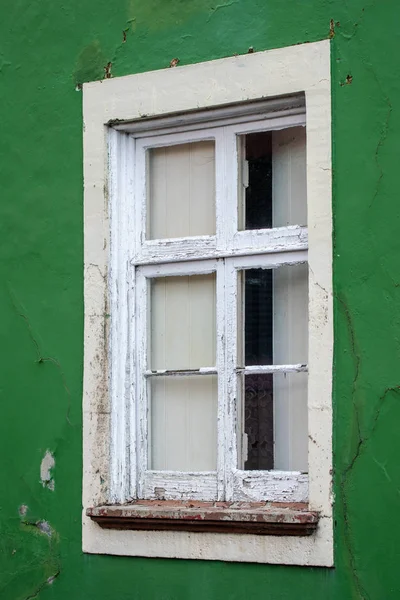 Old broken window on green wall