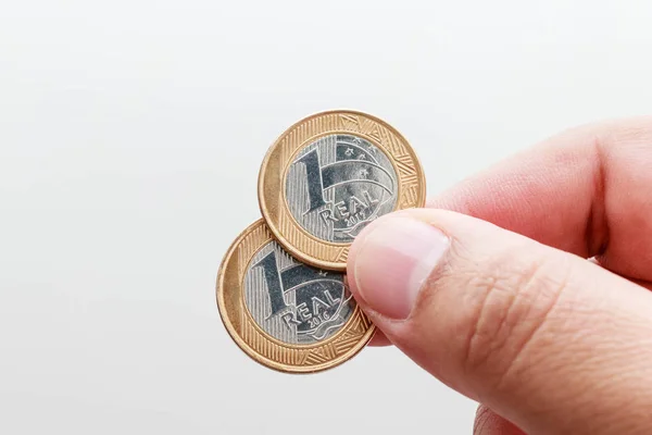 Erkek el holding bir gerçek yılının iki sikke, Brezilya para birimi beyaz arka plan