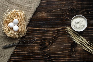 Beyaz bir kasede un, buğday, yumurta saman Nest, kopya alanı ile üstten görünüm kulaklı koyu ahşap arka plan. fırın ürünleri için malzemeler