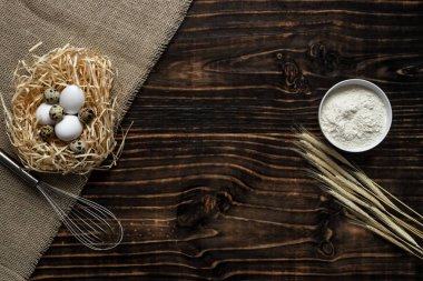 Beyaz bir kasede un, buğday, yumurta saman Nest, kopya alanı ile üstten görünüm kulaklı koyu ahşap arka plan. fırın ürünleri için malzemeler