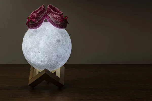 moon lamp and baby slipper on wooden table