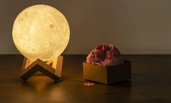 moon lamp and baby slipper on wooden table