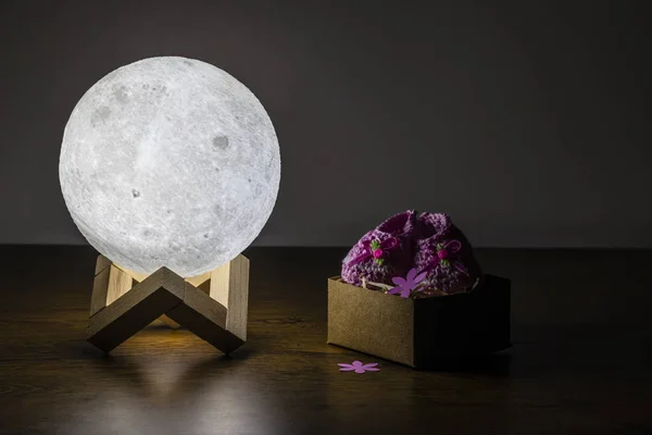 moon lamp and baby slipper on wooden table