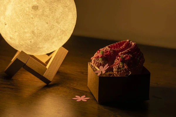 moon lamp and baby slipper on wooden table