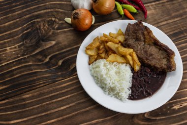 Beyaz plaka üzerinde yemek, pirinç, fasulye, biftek ve cips, ahşap arka plan