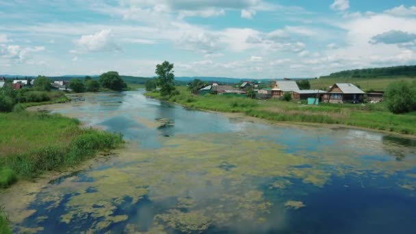 Vista aérea. Drone vuela sobre el río en la aldea en el soleado día de verano — Vídeos de Stock