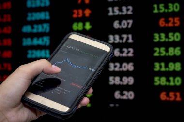 Borsa uygulama mobil çözümlenirken borsa verileri mobil genç işadamı Smartphone ve borsa grafik arka planı için.