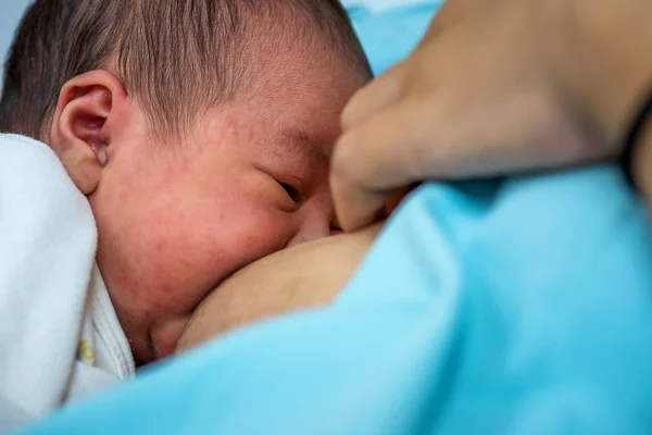 Young mother breastfeeding her newborn child in hospital after cesarean, breast milk