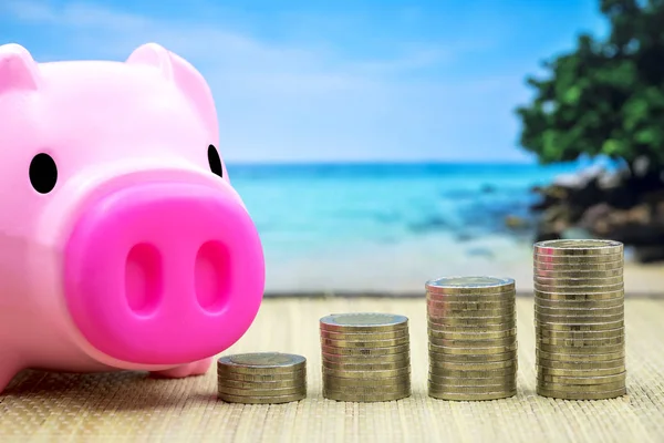 Budget vacation travel concept, piggy bank and stack coin on table with ocean background