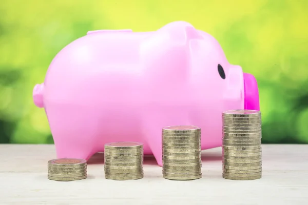Pink piggy bank for saving money with stack many coin