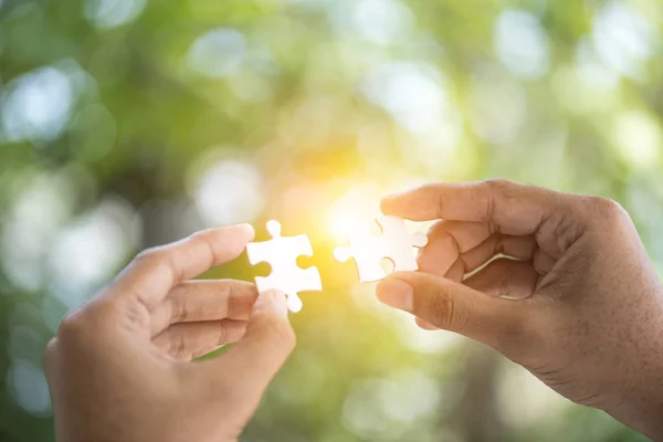 hand connecting jigsaw puzzle with sunlight affect, Business solutions, success and strategy concept