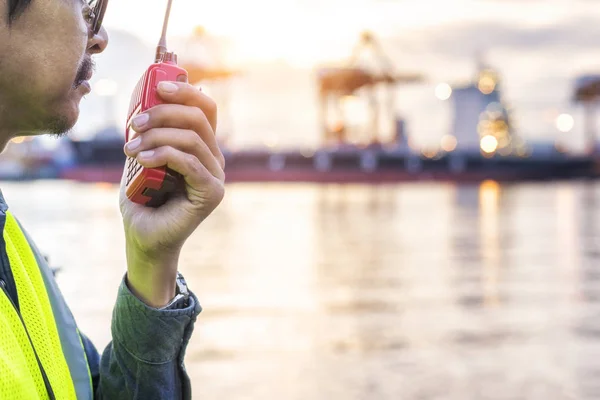 Cargo ship engineer using walkie-talkie in shipping yard