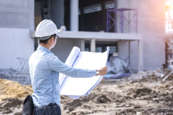 civil engineer working with blueprint for project quality control at construction site