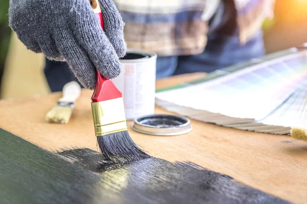 Paintbrush in hand and painting on the wooden table. Retro and vintage style, DIY and Hobby Concept