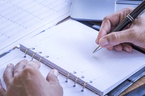businessman hands writing reminder task in the notebook paper, to do list of work