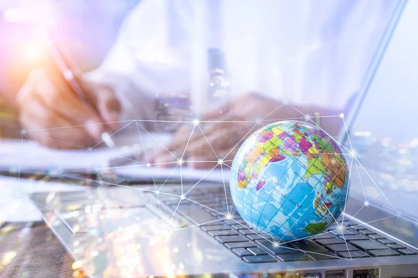 Double exposure small globe on computer laptop and businessman working with city light background