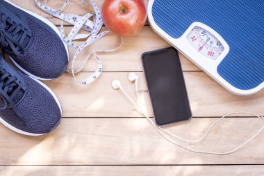 Siyah koşu ayakkabıları, kırmızı elma, beyaz bant ölçme ve tartma ahşap zemin üzerinde ölçekler. Spor aksesuar