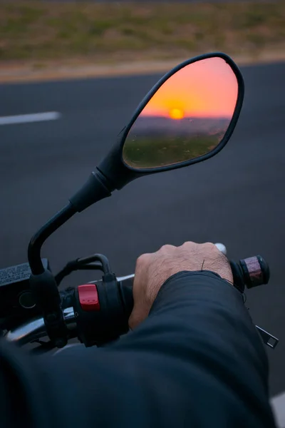 Siyah bir motosikletin önünde, aynaya yansıyan gün batımını görebileceğiniz bir gidon..