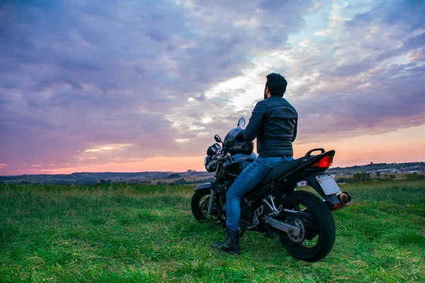 Mężczyzna Siedzący Czarnym Motocyklu Niebieskich Dżinsach Czarnej Kurtce Czarnym Hełmie — Zdjęcie stockowe