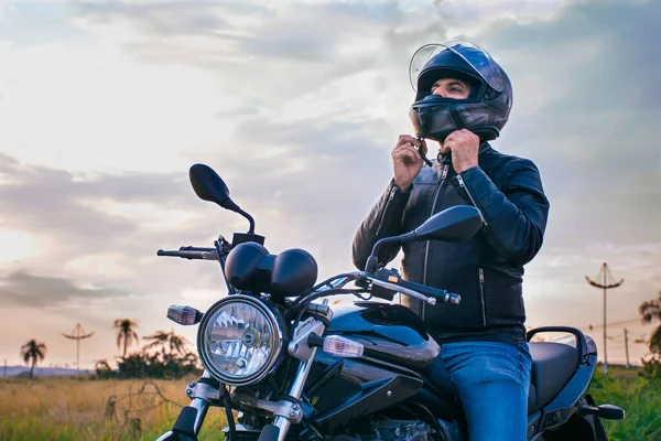 Man Sitting Motorcycle Wearing Jeans Black Jacket Fastening His Helmet — Stock Photo, Image