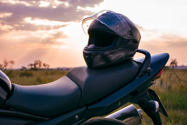 Siyah bir motosiklet kaskı, siyah bir motosikletin koltuğuna yerleştirilmiş..
