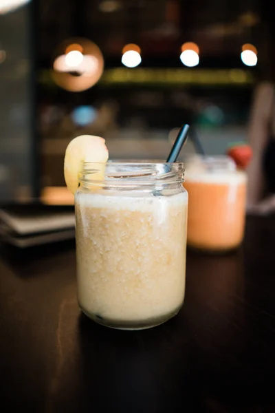 Lezzetli parlak sarı içecek saman ile yakından görmek kokteyl kavanoz koyu arka plan bulanık masaya yerleştirilen meyve ile dekore edilmiş servis 