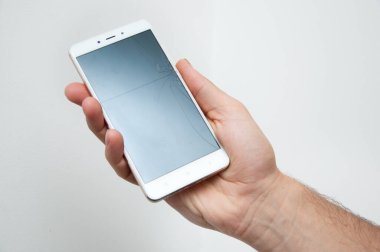 Beyaz akıllı telefon. Kırık ekranı olan erkek eli izole.