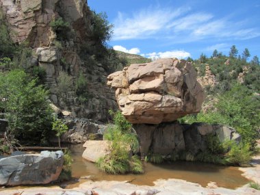 Giant boulder balanced on top of another rock formation seen on the Water Wheel Falls hiking trail in Payson, Arizona  clipart