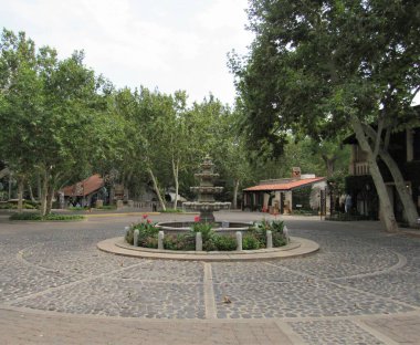 Sedona, Arizona 'da yer alan Tlaquepaque Sanat ve Alışveriş Köyü' nün arka planında bir çeşme ve ağaçlar var. 