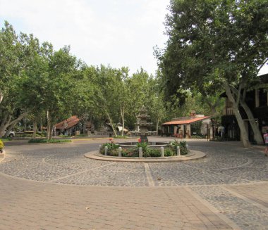 Sedona, Arizona 'da yer alan Tlaquepaque Sanat ve Alışveriş Köyü' nün arka planında bir çeşme ve ağaçlar var. 