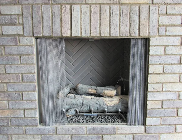 Closeup of an old stone fireplace on an outdoor patio with logs inside