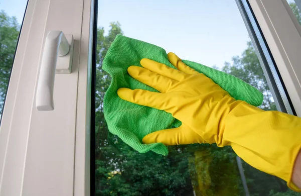 cleaning of plastic vinyl window with squeegee on green trees background