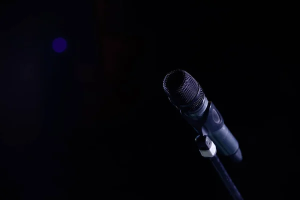 Closeup of microphone in concert hall or conference room on dark hall background