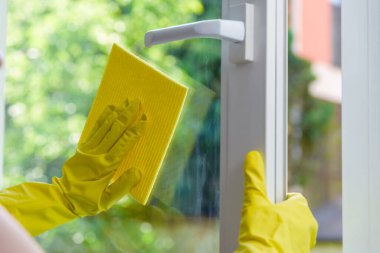 Açık vinil pencerenin temizlenmesi. Koruyucu eldiven ve temizlik bezi.