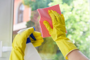 Kapalı plastik pencere temizliği. Ellerinde koruyucu sarı eldivenler ve serpiştirilmiş bez.