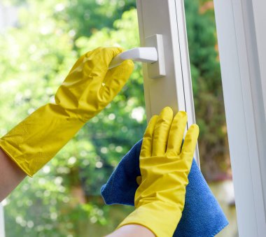 Açık plastik pencerenin temizlenmesi. Koruyucu eldiven ve temizlik bezi.