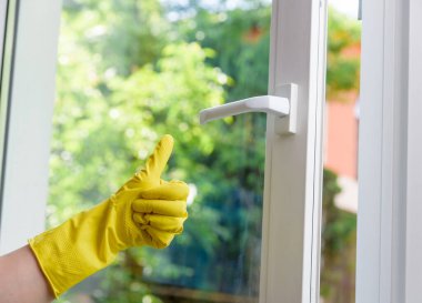 Koruyucu eldiven temiz plastik cam arka planında süper jest gösteriyor. Jest gibi baş parmak yukarı..